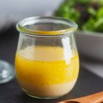 Basic vinaigrette in a small Weck jar with a salad behind it.