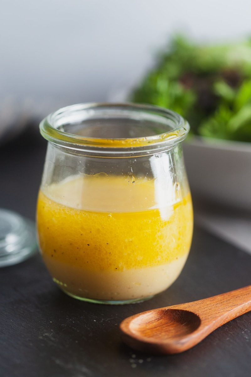 Basic vinaigrette in a small Weck jar with a salad behind it.