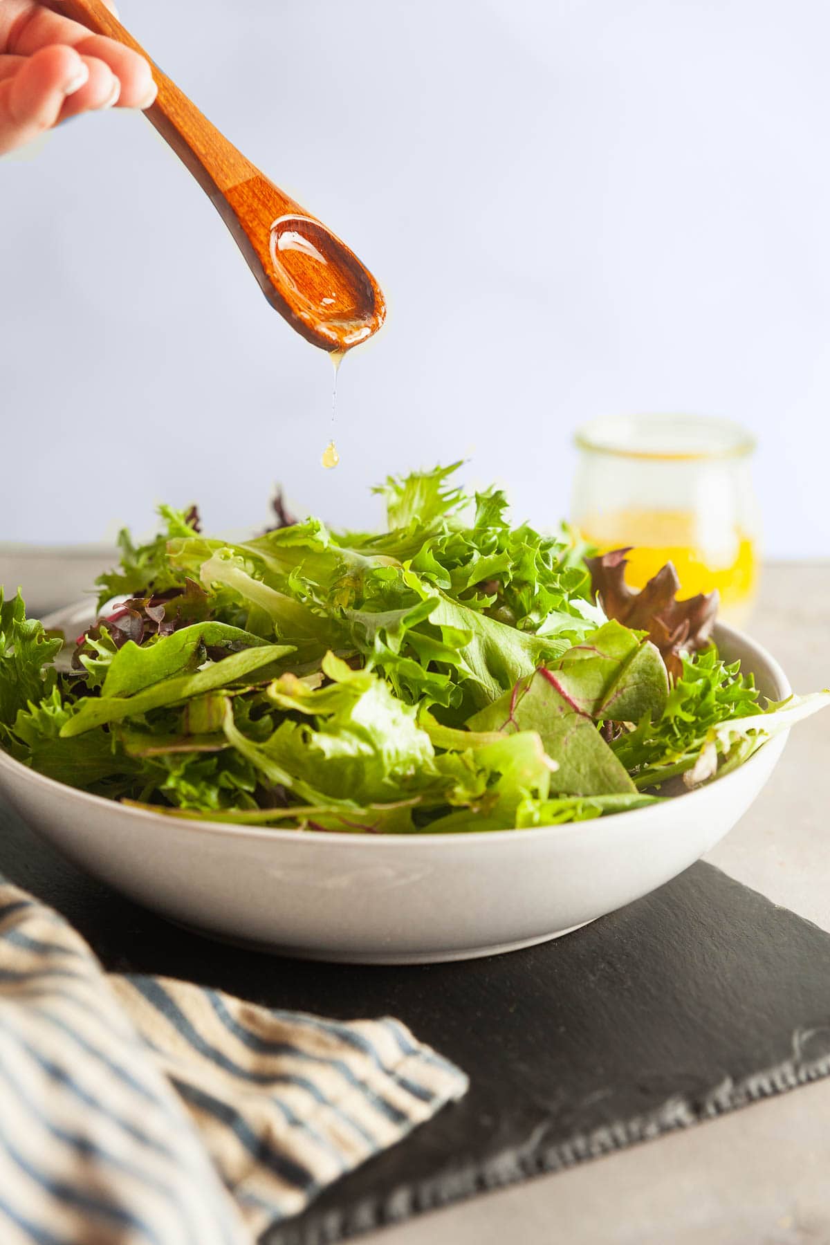 Drizzling homemade vinaigrette onto salad greens. 