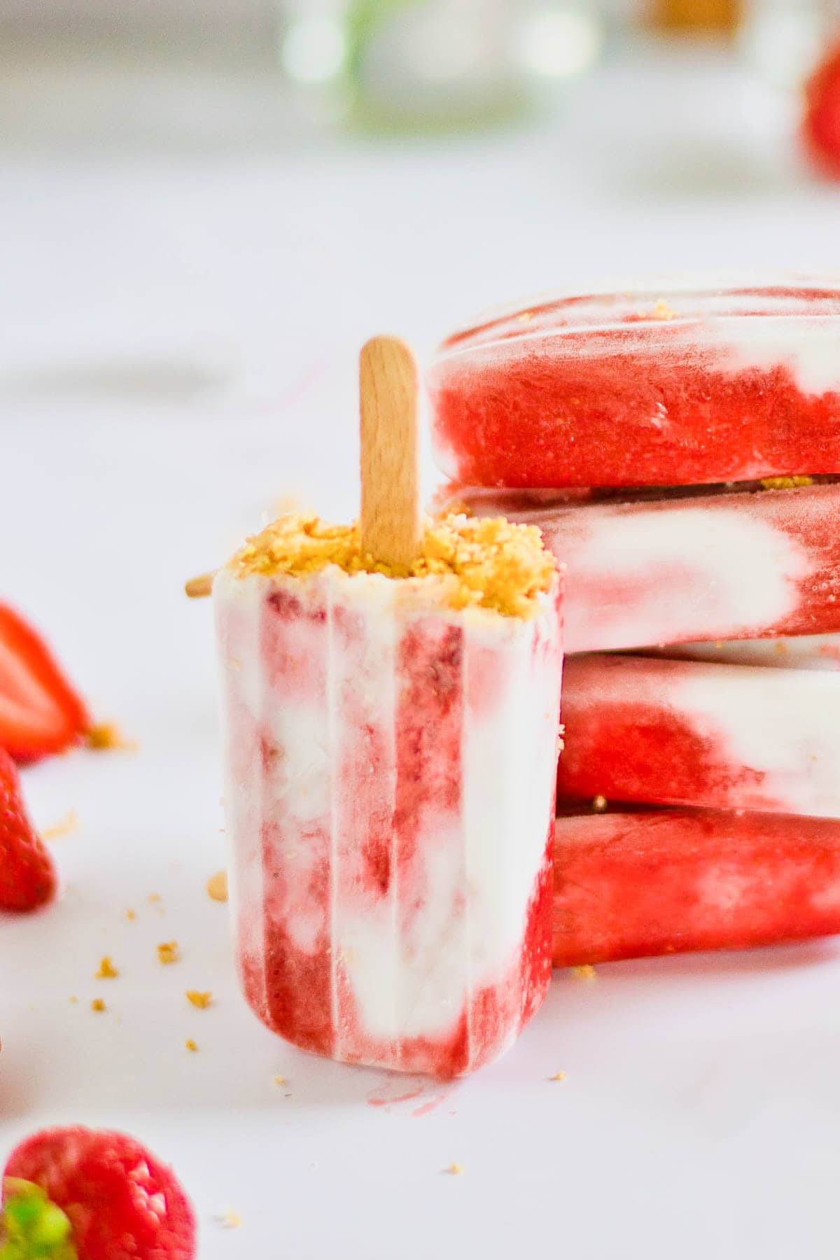 A stack of strawberry and coconut popsicles on a white marble board. 