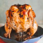 A portrait style photo of a cast iron skillet with beer can chicken.