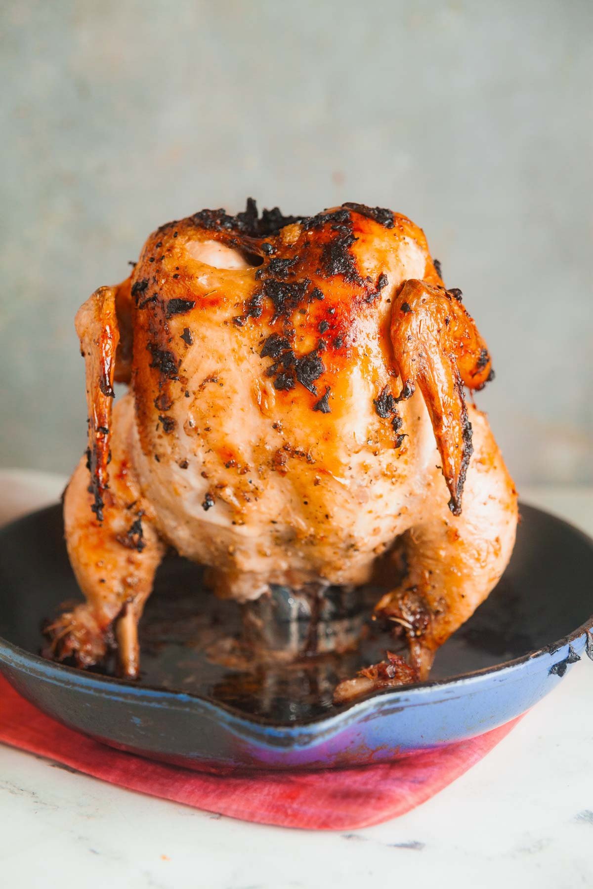 A portrait style photo of a cast iron skillet with beer can chicken. 