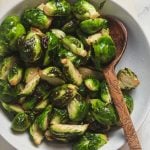 A white serving bowl filled with crispy air fryer brussels sprouts.