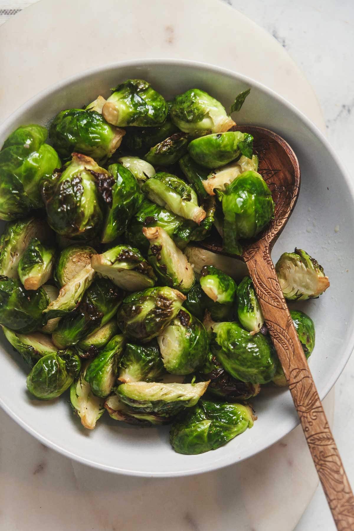 A white serving bowl filled with crispy air fryer brussels sprouts. 