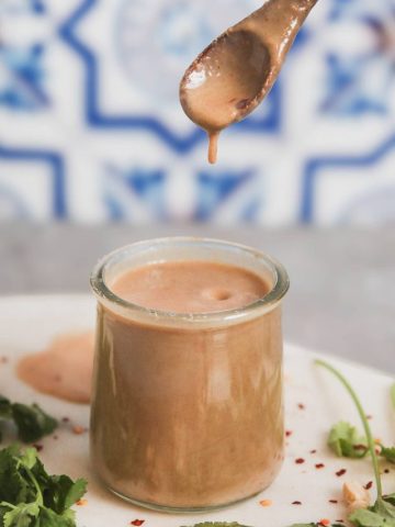 Peanut Sauce in a glass jar with a dripping spoon.