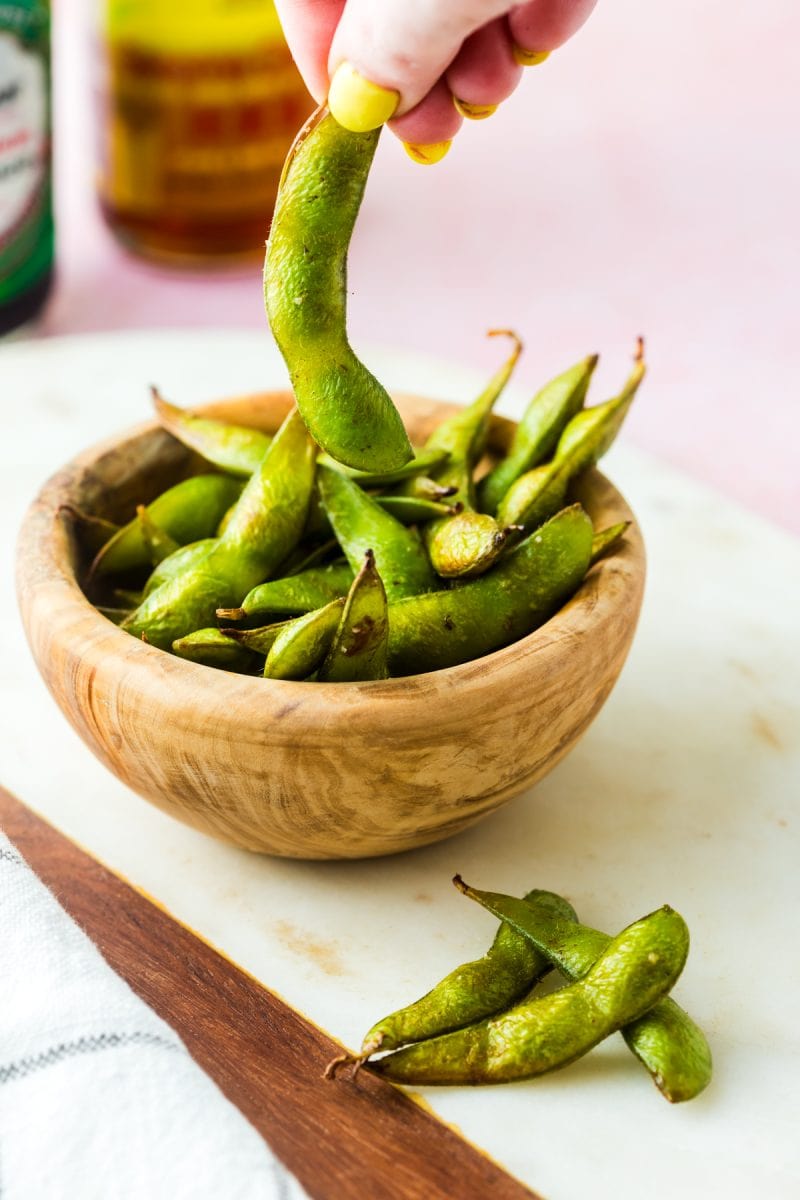 picking up a piece of edamame cooked in the air fryer.