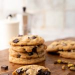 A stack of chewy pistachio chocolate chip cookies on a wooden background.