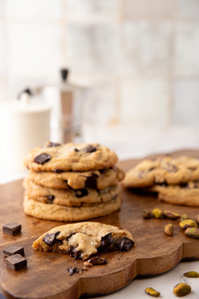 A stack of chewy pistachio chocolate chip cookies on a wooden background.