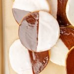 A baking sheet with frosted black and white cookies.