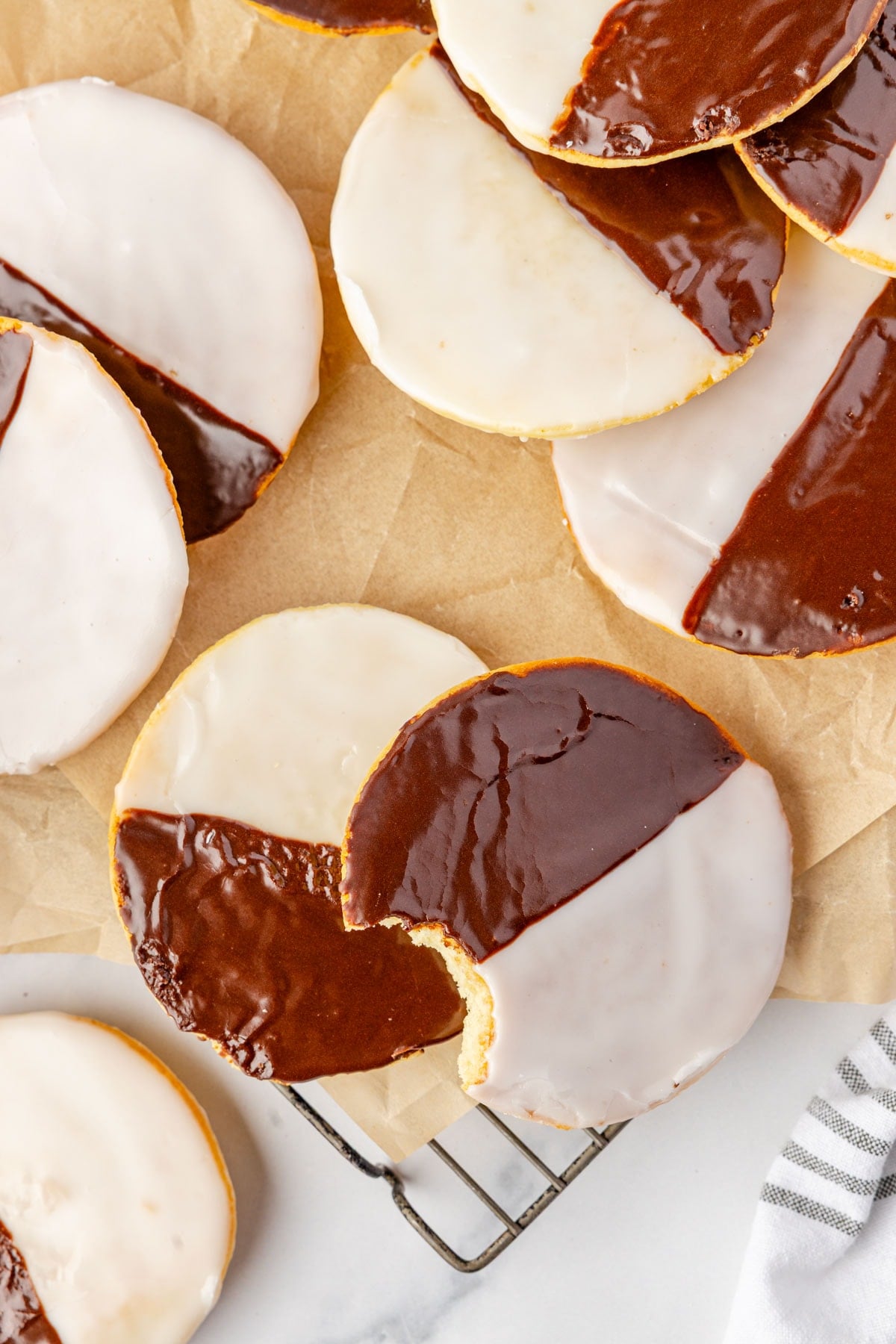A platter of New York Black and White Cookies, one with a bite taken from it.
